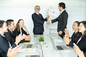 Senior Boss or CEO promoting young subordinate. Two businessmen handshaking, congratulating on...