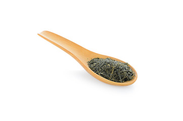 Dry tea with green leaves in wooden spoons on white background