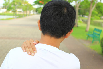 Close up of Man with shoulder pain or neck pain in the public park,Health concept