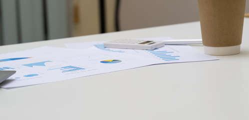 business chart lay on white table with labtop, pen, calculator and coffee cup