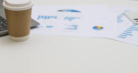 Fototapeta premium business chart lay on white table with coffee cup, notebook and pen