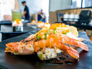 Sushi Shrimp burn the fire (Aburi River Prawn) and Aburi Salmon sushi with sauce and Tamagoyaki Sandwich put on a black plate in Japanese restaurant.