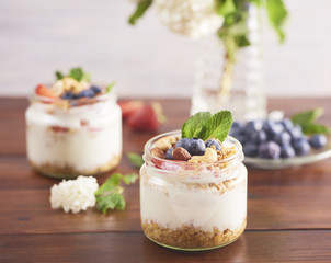 Homemade Greek yogurt with granola, mint, blueberries and strawberry in a glass jar