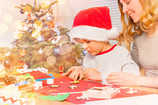 Little boy decorating Christmas ornaments with mom