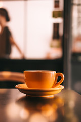 Flat white coffee in yellow cup on a wooden table at the hipster coffee shop. Dark food photo. Vintage color filter effect. Copyspace; vertical