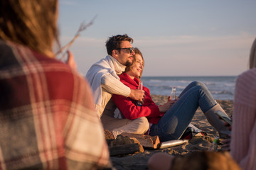 Fototapeta premium Couple enjoying with friends at sunset on the beach
