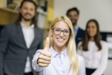 Young businesswoman with thumb up standing in the office