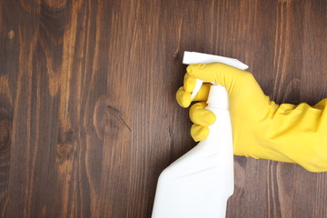 yellow glove and a white bottle sprayer on a wooden background