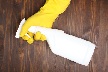 yellow glove and a white bottle sprayer on a wooden background