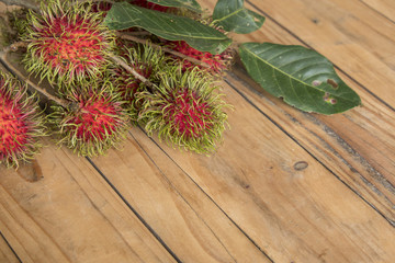 Red rambutan Nephelium lappaceum on broun board. Fruit tropical tree of the family Sapindaceae , native to South - East Asia , cultivated in many countries in the region