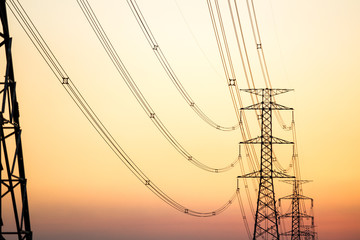 High voltage power tower close up on the worm tone sky before sunset.