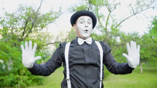 Funny mime is crooking on camera in the park