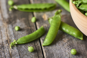 Cloce-up view of Hearthy fresh green peas and pods in wooden bowl on rustic  background