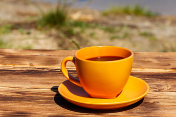 Cup of coffee on the wooden table near the river