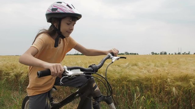 Child on a bicycle. A little girl is riding a bicycle on a wheat field.