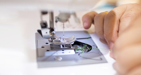 Close up - Female tailor working with sewing machine..Profestional woman hands during sewing work with yarn on sewing machine.