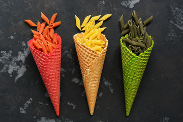 Colored pasta in waffle cones on a dark concrete background. Concept. Top view.