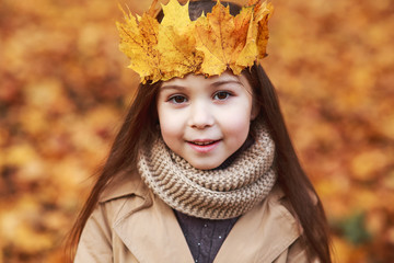 Portrait liitle cute girl with crown of leaves in autumn park