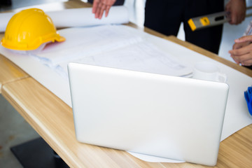 Engineers working on a blueprint and a laptop computer.