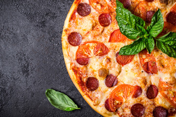 Pizza pereroni and basil on black background closeup