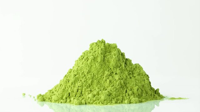 Heap of matcha green tea ground on turntable, closeup on white background