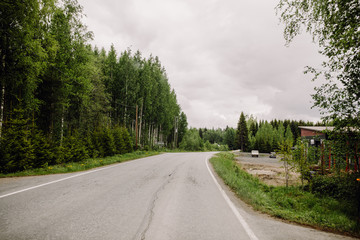 Fototapeta na wymiar Countryroad in finnish lapland during midsummer with green trees and dark clouds