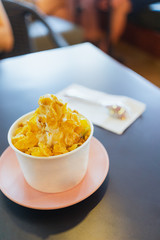 Cup of frozen yogurt with toping on the table.