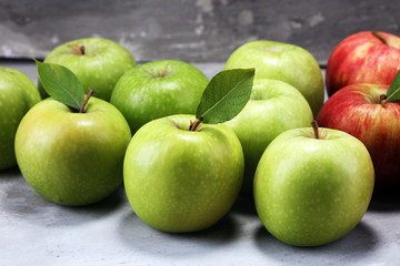 Ripe red apples with leaves on wooden background.