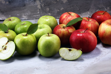 Ripe red apples with leaves on wooden background.