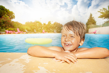 Happy boy relaxing at the swimming pool edge