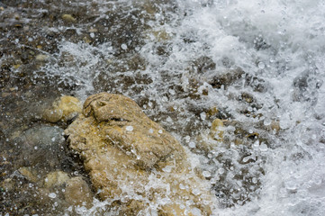 pebble stones on the sea beach, the rolling waves of the sea with foam