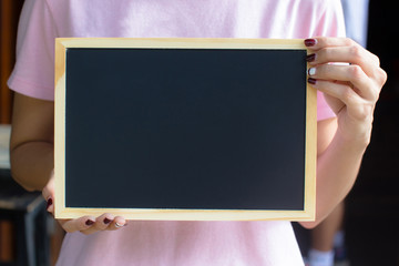 Female hand holding small blackboard, chalkboard with empty or copy space for text.