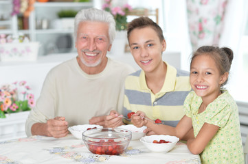 grandfather and grandchildren eating fresh strawberries