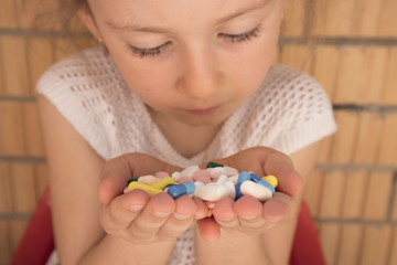 Obraz na płótnie Canvas little girl holding a pill in her hands