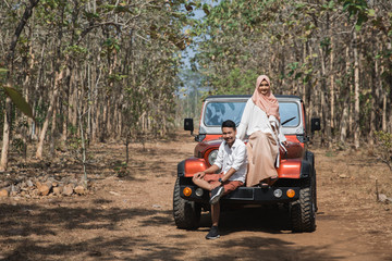 woman and man sitting on top of a car
