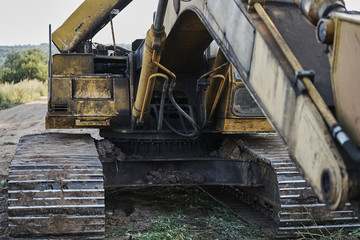 Fototapeta na wymiar Old yellow excavator on a dirt road