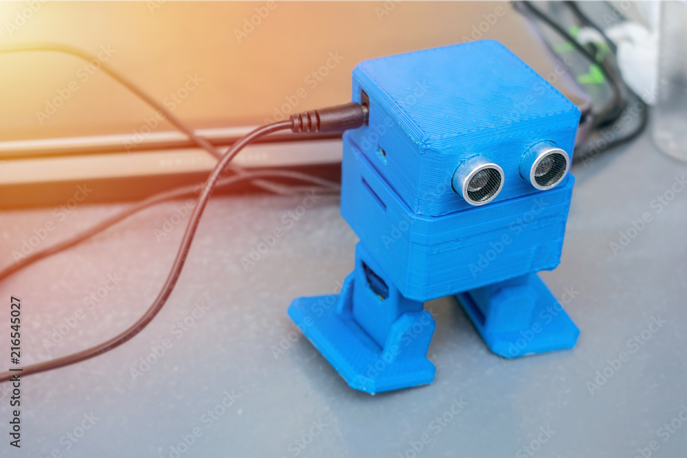 Poster funny dancing blue robot, printed on the 3d printer on the background of devices and cords. the robo