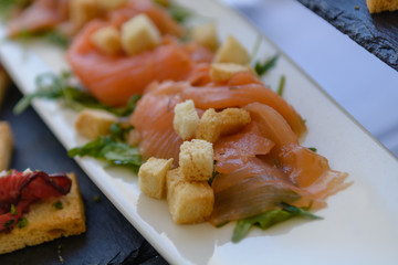 Raw salmon slices with toasted bread on white plate