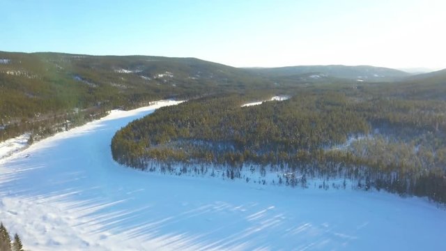 Aerial drone panoramic view of traditional houses, forest and fields in the snow in northern Norway. Cold snowy sunny winter.
