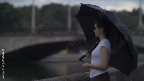 Sad Girl With An Umbrella Stands Near A Small River In The