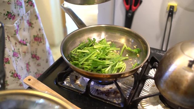 Frying green vegetable in a non stick pan at home, Los Angeles