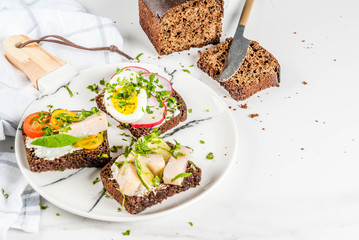 Set of various danish open sandwiches Smorrebrod with fish, egg and fresh vegetables, white marble background copy space