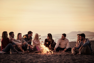 Group Of Young Friends Sitting By The Fire at beach