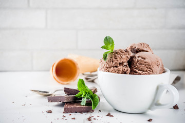 Homemade chocolate ice cream served with fresh mint, dark chocolate and waffle ice cream cones, white marble background copy space