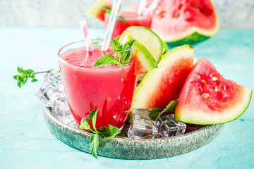 Fruity summer cold drink, homemade watermelon juice or smoothie served with lime and fresh mint leaves, light blue trendy background copy space
