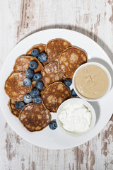 pancakes with peanut butter and yoghurt on white background, vertical top view