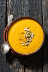 pumpkin soup on wooden background, vertical top view
