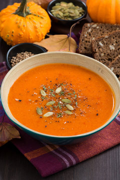 pumpkin soup in a bowl on wooden table, vertical