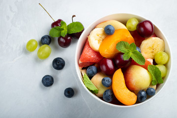 Obraz na płótnie Canvas Bowl of healthy fresh fruit salad on a white background. Top view with copy space. Flat lay