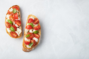 Bruschetta with tomatoes, mozzarella cheese and basil on a light background. Traditional italian appetizer or snack, antipasto. Top view with copy space. Flat lay - obrazy, fototapety, plakaty